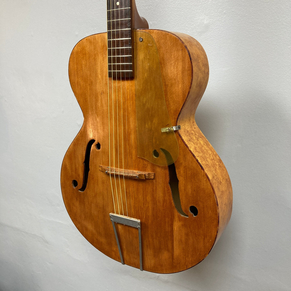 Playtime by Harmony Vintage Archtop Guitar from the 1940s, displayed on a wall, showcasing its classic design and smooth strings.