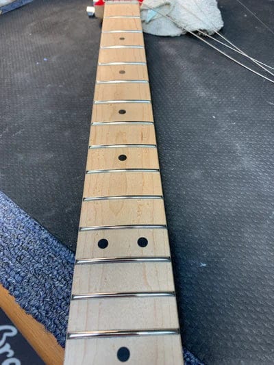 Close-up of a guitar neck on a table, highlighting the Premium Setup service for optimal performance and playability enhancements.