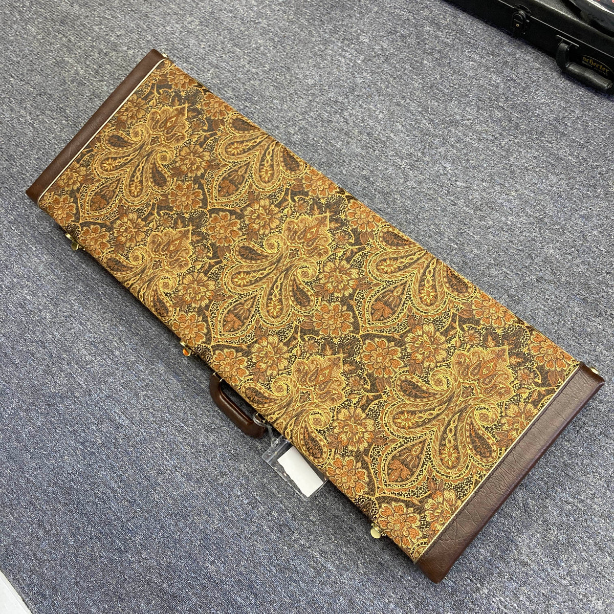 A rectangular case featuring paisley-patterned fabric, brown edges, and a sturdy handle—ideal for storing your PRS Custom 24 Angry Larry 2011 w/Case Used electric guitar by PRS—rests atop a gray carpeted floor.