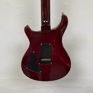 The back of a red PRS Custom 24 Angry Larry 2011 electric guitar by PRS, featuring two black plastic cover plates and a visible neck joint, shown against a plain white wall.