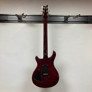 A PRS Custom 24 Angry Larry 2011 electric guitar by PRS hangs on a wall mount, displayed from the back to showcase its dark glossy finish and black plastic backplates.