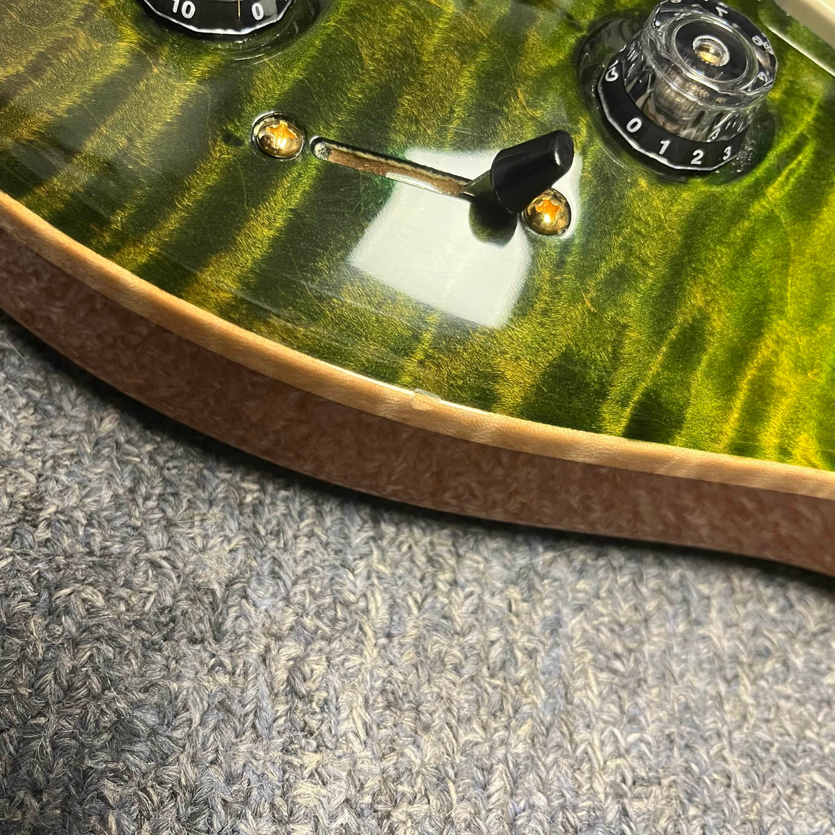 Close-up of a PRS P22 Artisan Piezo Green Fade 2013 electric guitar body, showing the switch, knobs, humbucker pickups, and a small edge chip, resting on textured gray fabric.