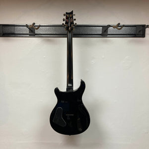 PRS SE Mark Holcomb - Holcomb Blue Burst w/Gigbag Used Consign by PRS hanging on a wall rack, photographed from the back against a plain white wall.