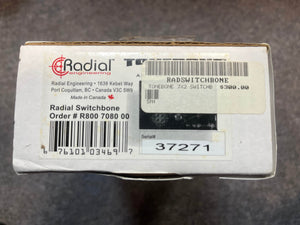 A white box labeled "Radial Tonebone Switchbone JX-2 AB-Y Class-A Switcher (Preowned)" by Radial Engineering, with a $300 price tag, plus order and serial numbers and company address.