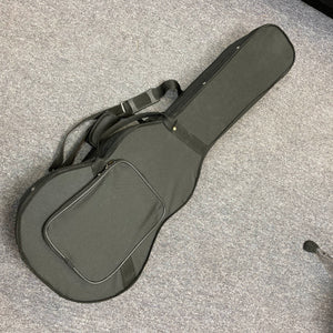 Republic Parlor Resolian Antique Bronze Resonator guitar in its soft black case, featuring a front pocket and shoulder strap, designed to fit this single cone parlor model by Republic, shown lying on a gray carpeted floor.