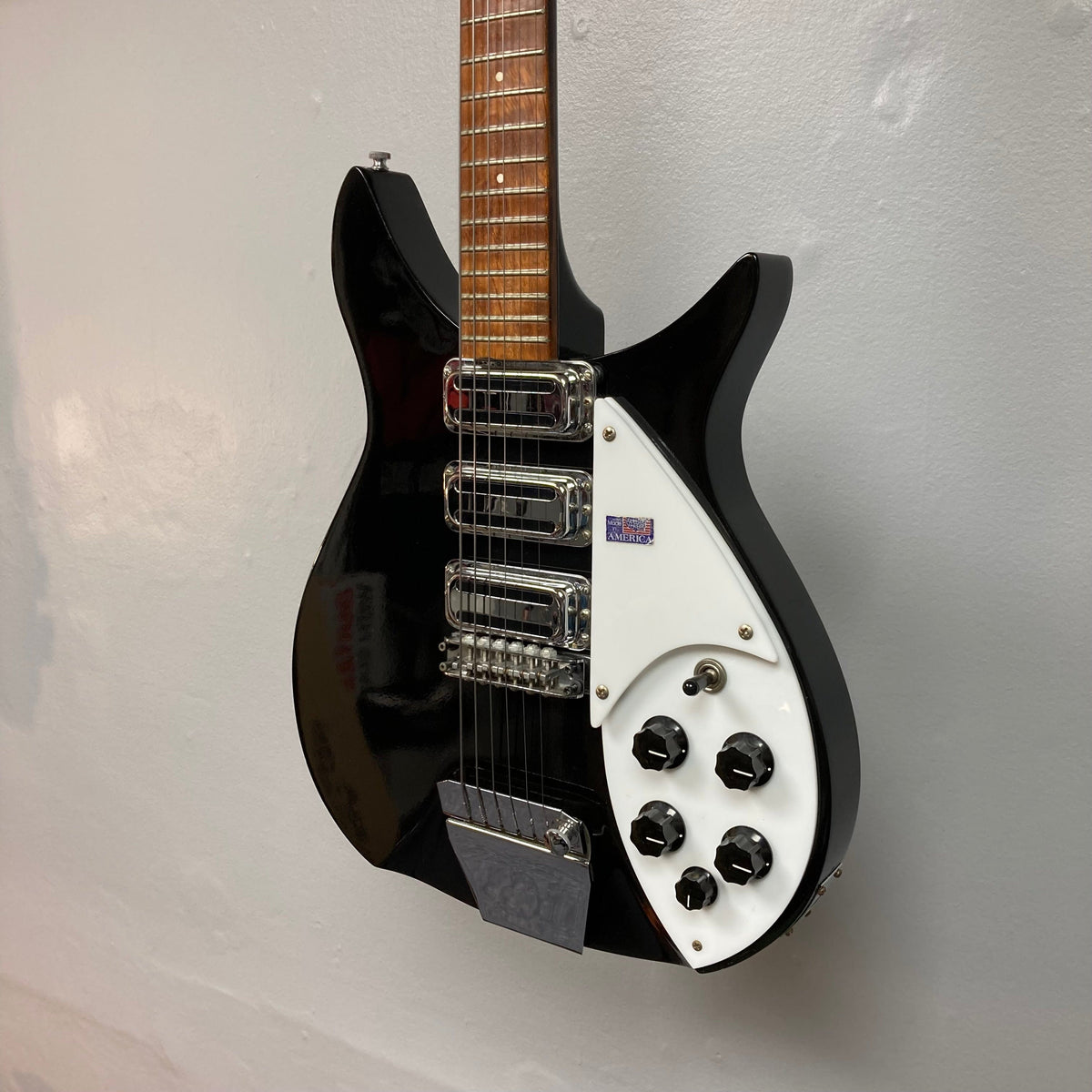 Rickenbacker 325C64 Jetglo guitar displayed on a wall, showcasing its classic design and iconic silhouette.