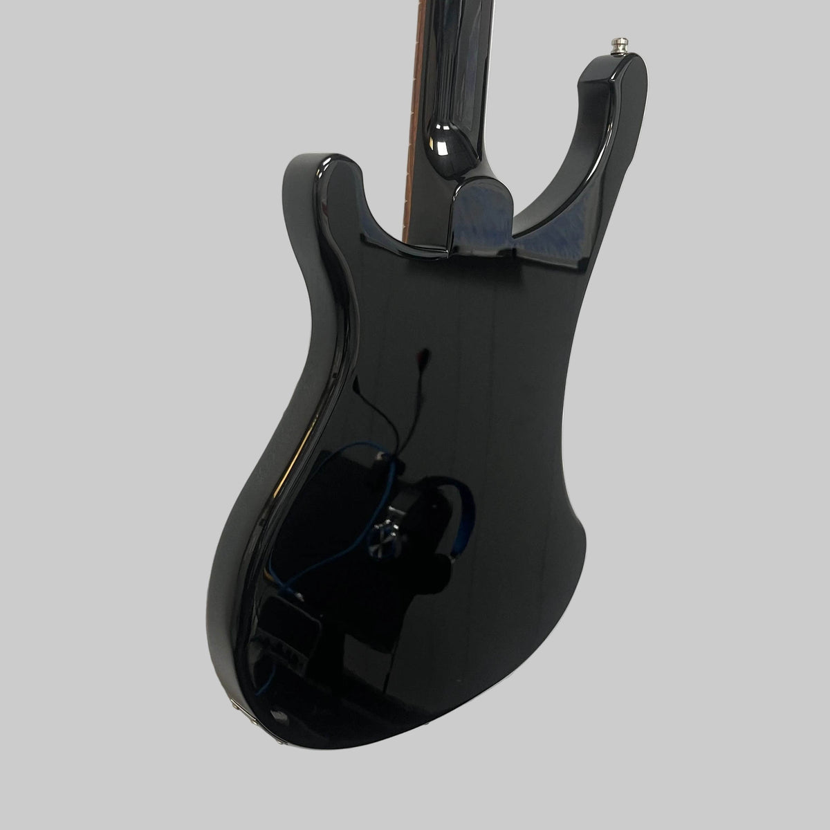 A black electric guitar is mounted on a white wall next to a red electric guitar, while a vintage bass guitar—like the Rickenbacker 4003 Bass Guitar – 2020 Jetglo w/Case by Rickenbacker—completes the striking display.