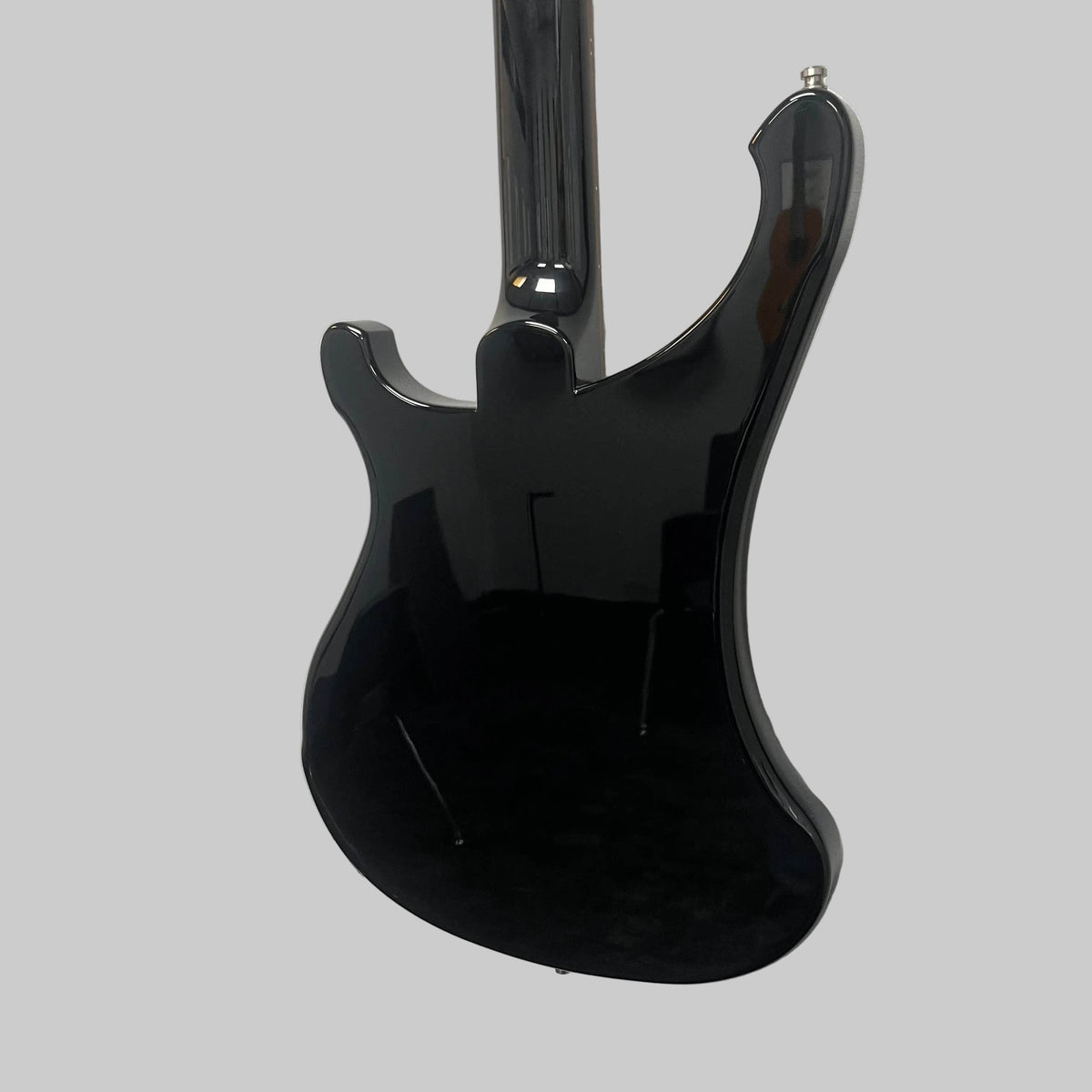 A Rickenbacker 4003 Bass Guitar – 2020 Jetglo w/Case by Rickenbacker is hanging on a white wall, photographed from the back to showcase its glossy black finish and the reflections of the room.