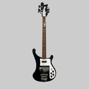 A Rickenbacker 4003 Bass Guitar – 2020 Jetglo w/Case and a red Fender Stratocaster electric guitar hang on a wall-mounted rack against a gray wall.