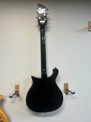 A near-mint Rickenbacker 620 – Jetglo – w/ Original Case hangs on a white wall, shown from the back, flanked by two empty wall mounts.