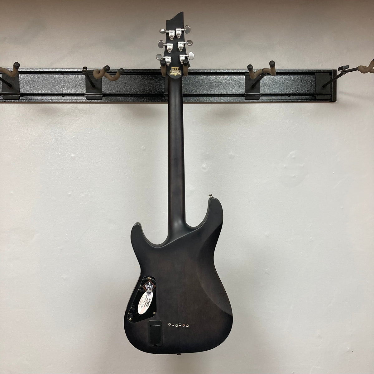 Schecter C-1 Platinum Translucent Black Used electric guitar displayed on a wall, featuring a double-cutaway design and EMG Active 81/85 pickups.