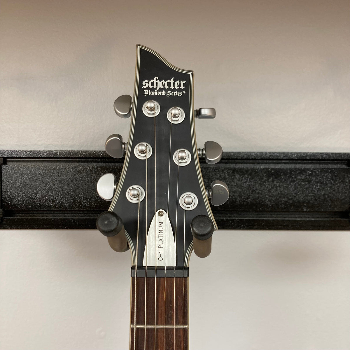 Schecter C-1 Platinum Translucent Black Used, featuring a quilted maple top, three-piece maple neck, and EMG Active 81/85 pickups on a stand.