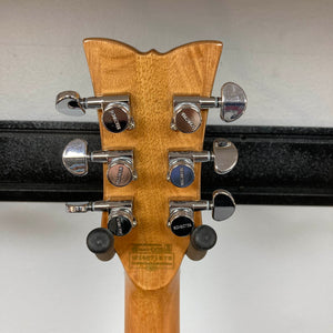The back of a Schecter Solo-II Custom Trans Black Burst w/Case Used guitar headstock displays six chrome Schaller tuners on a light wood neck, with its dark burst finish reflecting against a white wall.