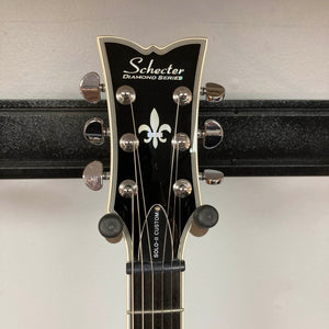 Close-up of a Schecter Solo-II Custom Trans Black Burst headstock with tuning pegs and fleur-de-lis inlay—featuring premium Schecter USA Pasadena pickups.