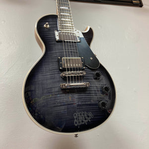 A used Schecter Solo-II Custom Trans Black Burst w/Case, featuring chrome hardware and four black knobs, USA Pasadena pickups, is displayed mounted on a white wall.