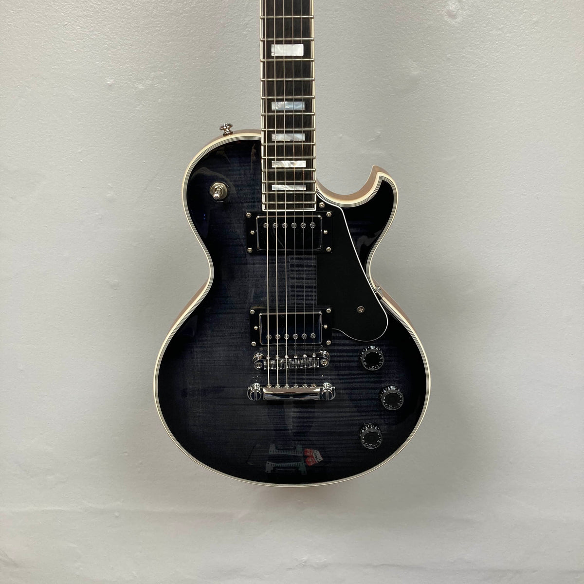 A used Schecter Solo-II Custom electric guitar in Trans Black Burst finish with chrome hardware and Pasadena pickups, displayed against a light gray wall; includes case.