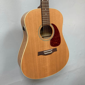The Seagull S6 QI Slim Acoustic Guitar w/Hard Case - USED/consign features a solid spruce top, six strings, and a reddish-brown pickguard, shown mounted against a light gray wall.