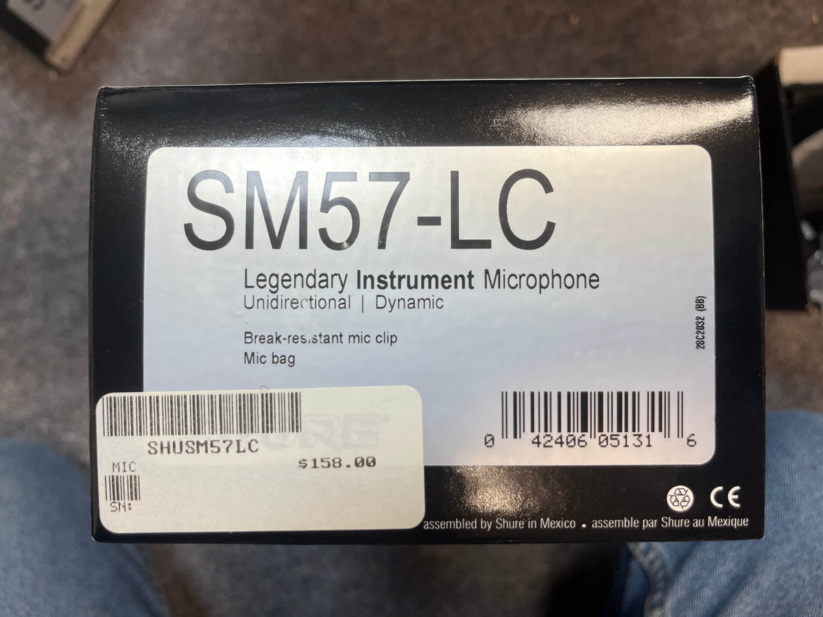 Box of a used Shure SM57-LC Legendary Instrument Microphone by Shure, showing product label, barcode, $158 price tag, and included accessories: mic clip and mic bag.
