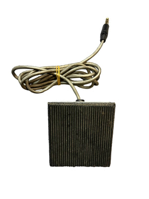 The Silvertone 1484 Tremolo Reverb Footswitch 1960s in gray is a rectangular, ribbed pedal with a cord and 1/4-inch jack, evoking vintage Silvertone style. Pictured against a white background.
