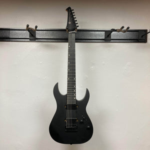 Spira S-407 MBK Matte Black Electric Guitar with double-horn shape and custom humbuckers on a wall-mounted rack, showcasing its sleek design and extended-range features.