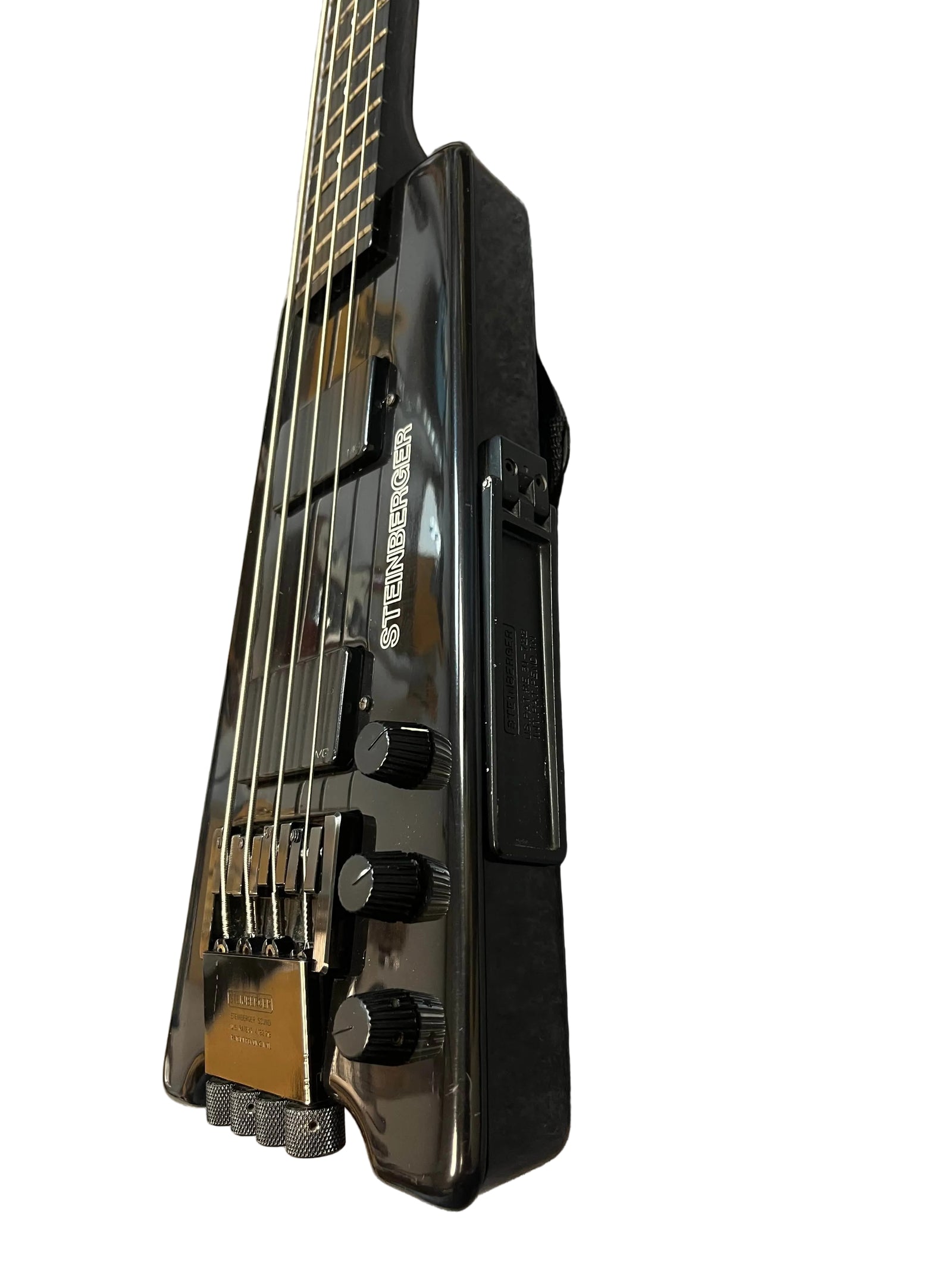 Close-up of a 1984 Steinberger XL-2 Bass USA, an iconic black headless bass, highlighting its pickups, bridge, control knobs, and part of the neck against a white background.