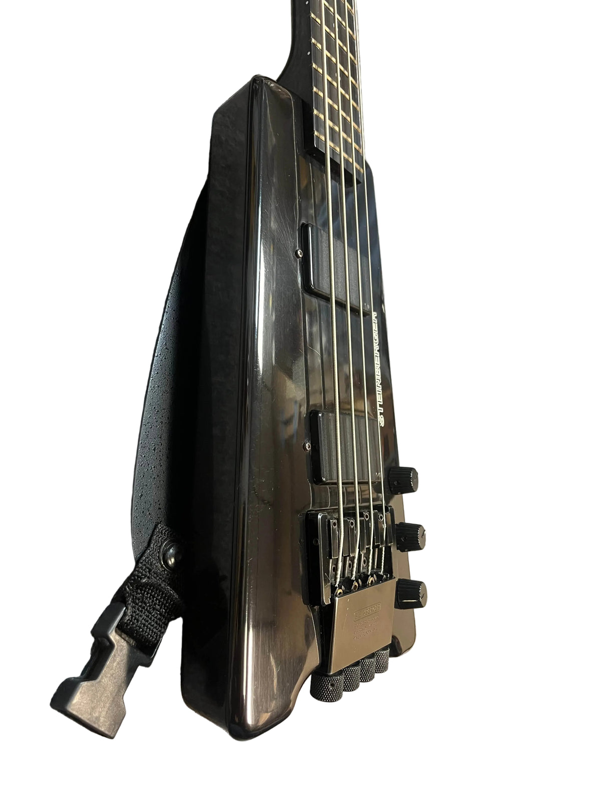 Close-up of a black 1984 Steinberger XL-2 Bass USA, a headless four-string bass guitar by Steinberger, highlighting the bridge, knobs, and strap detail against a white background.