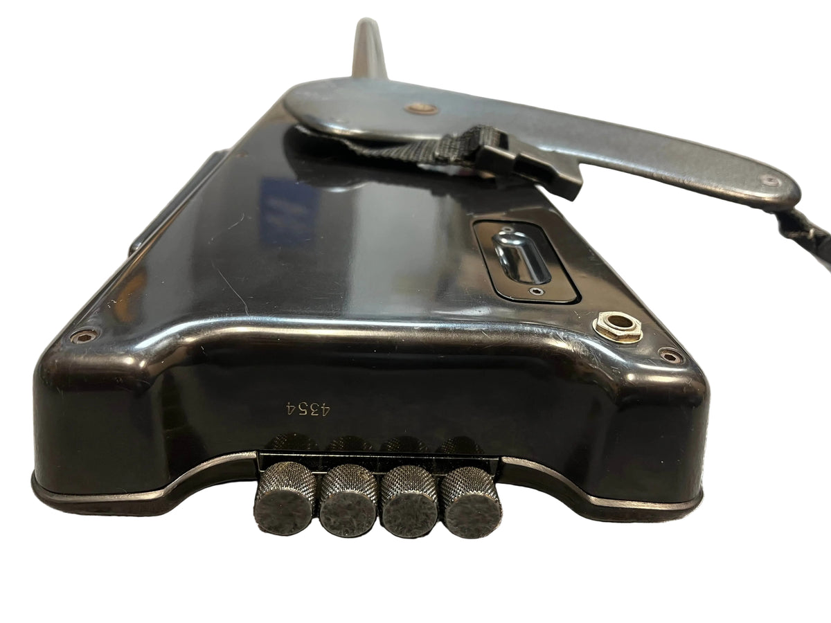 A close-up of a black handheld mechanical device with five textured metal rods, a grip, strap, and switch, echoing the sleek look of the iconic 1984 Steinberger XL-2 Bass by Steinberger USA.