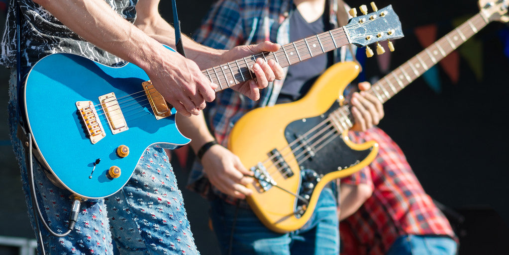 Rock musicians on stage playing guitar and bass.