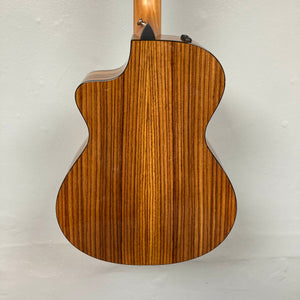 A close-up of the Taylor 212ce Plus w/Gigbag Used Consign highlights its natural wood grain back and elegant cutaway design.