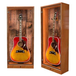 Two ShowCase™ Deluxe Guitar Display Cabinets by A&S Crafted Products, each showcasing a sunburst acoustic guitar behind glass against rustic wood—ideal for museum-quality presentation and optional humidity control.