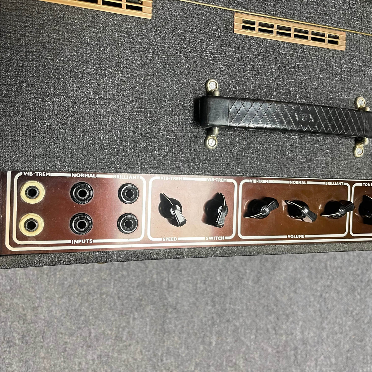 Close-up of a Vintage 1963 Vox AC30/6 Normal by Vox, showing its control panel with input jacks, speed and volume knobs, Woden transformers, the original JMI egg footswitch, handle, and flight case on the textured black surface.