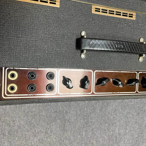 Close-up of a Vintage 1963 Vox AC30/6 Normal by Vox, showing its control panel with input jacks, speed and volume knobs, Woden transformers, the original JMI egg footswitch, handle, and flight case on the textured black surface.