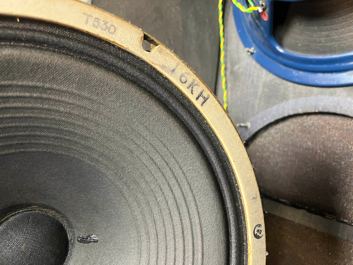 Close-up of a speaker cone marked "T830" and "6KH," with parts of another speaker—likely a Celestion Blue T530—and twisted wires, evoking the classic Vox AC30/6 setup, as seen in the Vintage 1963 Vox AC30/6 Normal by Vox.