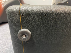 Close-up of the corner of a textured black Marshall 1969 4x12 Cabinet with matching Celestion T1281 Greenbacks, showing two small holes above a round plastic foot.