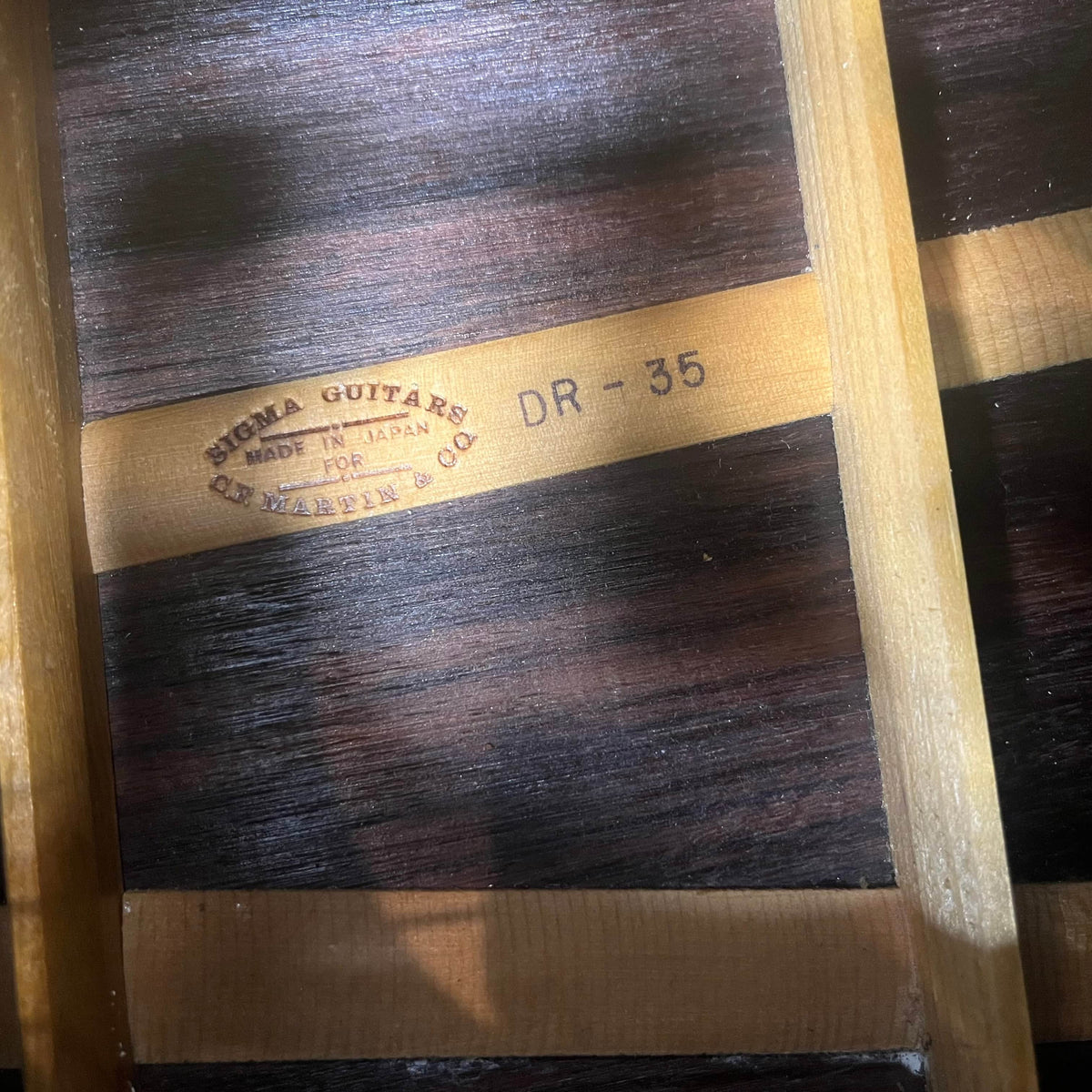Close-up of a Vintage Sigma DR-35 Acoustic Guitar interior shows the "SIGMA GUITARS MADE IN JAPAN FOR C.F. MARTIN & CO. DR-35" stamp, wood braces, and grain, highlighting this Sigma model inspired by the Martin D-35. Includes case.