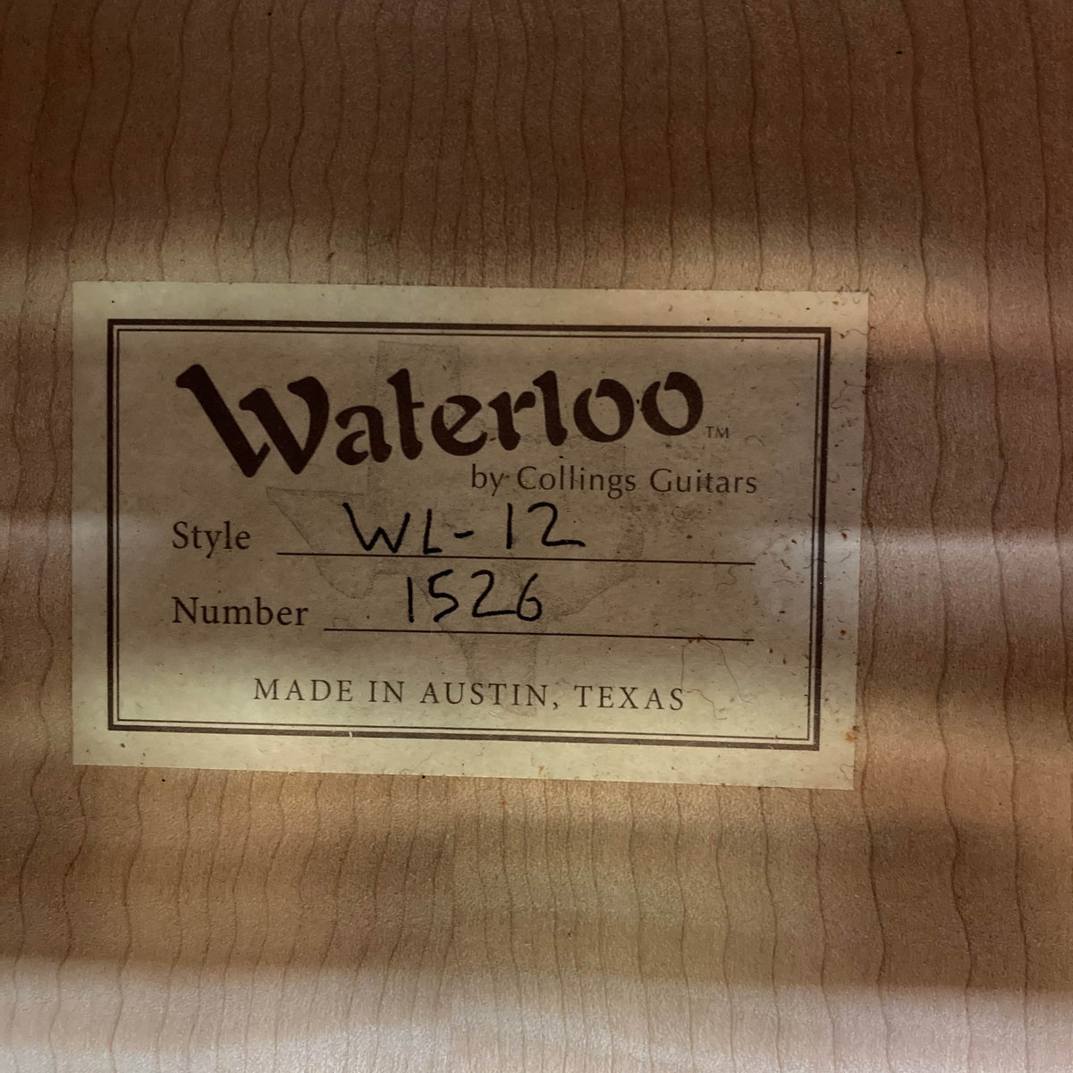 A label inside the Waterloo WL-12 Parlor Acoustic w/Case by Waterloo reads, "Waterloo by Collings Guitars. Style WL-12. Number 1526. Made in Austin, Texas," affixed to the beautifully grained wood interior.