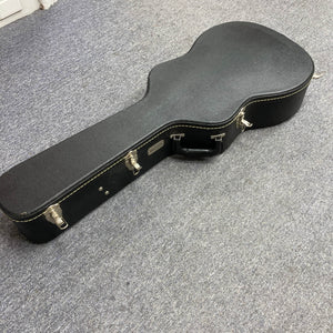 A Waterloo WL-12 Parlor Acoustic used consign guitar case with metal latches and a handle is lying closed on a gray carpeted floor.