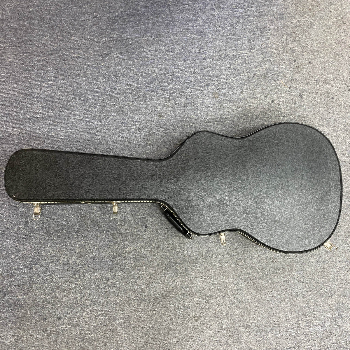 A Waterloo WL-12 Parlor Acoustic w/Case (Used, Consign) by Waterloo, featuring a black hard-shell case with metal latches, is closed and resting on a gray carpeted floor.