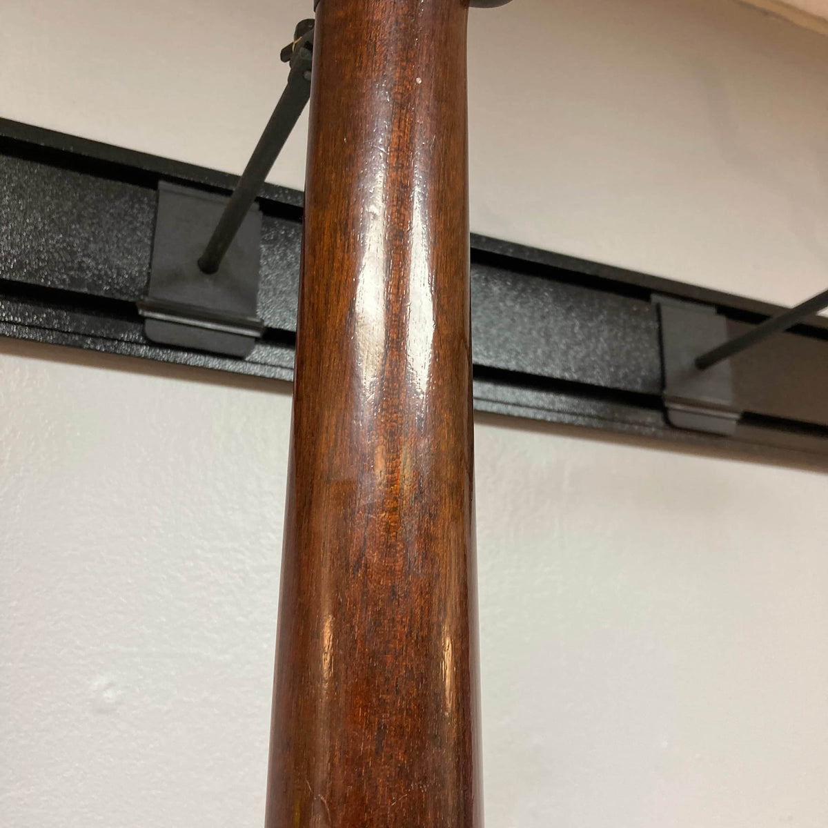 Close-up of the wooden neck on a Waterloo WL-12 Parlor Acoustic w/Case Used Consign guitar, showing its glossy finish. A white wall and black mounting bracket are in the background. Brand: Waterloo.