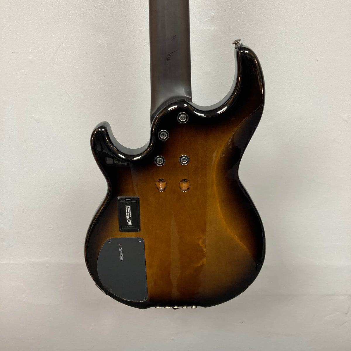 The image shows the back of a Yamaha BB735A Electric 5-String Bass Coffee Sunburst (Blem Discount) with electronics cover plate, neck joint screws, and two empty knob holes, set against a plain white wall.