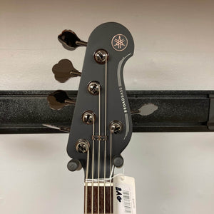 Close-up of the Yamaha BB735A Electric 5-String Bass Coffee Sunburst headstock, displaying four tuning pegs, the Yamaha logo, “BROADBASS” marking, and a white “106” tag attached to one of the pegs.
