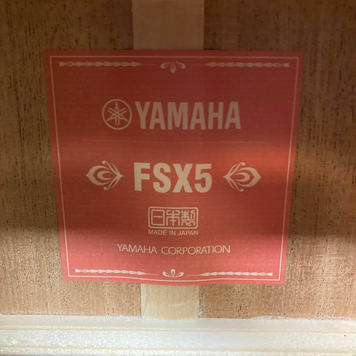 A close-up shows the Yamaha logo, model FSX5 Satin Red Label Natural, &quot;Made in Japan,&quot; and &quot;Yamaha Corporation&quot; on this used premium acoustic electric guitar with case.