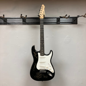 ZZ Top Signed Strat Style Guitar on wall hook, featuring signatures from Billy Gibbons, Dusty Hill, and Frank Beard.