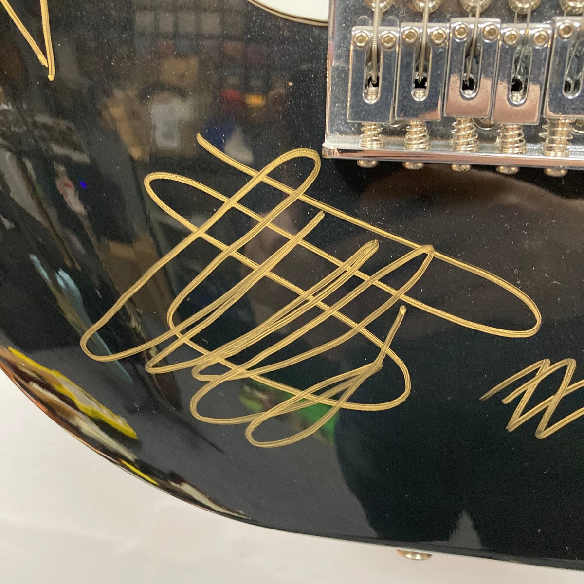 Close-up of a ZZ Top signed Strat-style guitar bridge, featuring signatures from Billy Gibbons, Dusty Hill, and Frank Beard.