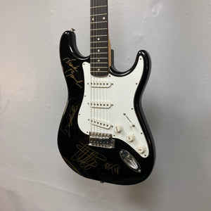 ZZ Top Signed Strat Style Guitar displayed on a wall, featuring autographs from Billy Gibbons, Dusty Hill, and Frank Beard.