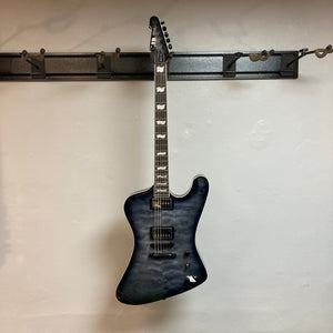 Blue ESP LTD Phoenix-1000 QM electric guitar with white binding and quilted maple top, displayed on a wall.