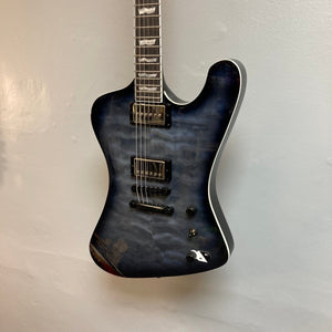 Blue ESP LTD Phoenix-1000 QM electric guitar with quilted maple top, displayed on a wall, highlighting the see-thru black sunburst finish and intricate detailing.