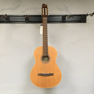 Godin Etude Classical Guitar, solid cedar top, rosewood fingerboard, displayed on a wall, showcasing its detailed craftsmanship and premium materials.