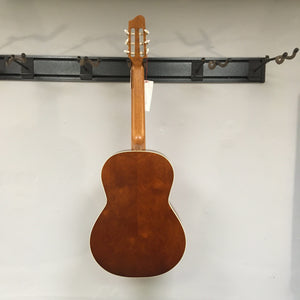 Godin Etude Classical Guitar, full-size, on a hook with a tag, showcasing its solid cedar top and Canadian wild cherry back.