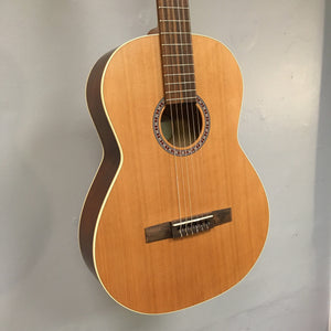 Godin Etude Classical Guitar with solid cedar top and rosewood fingerboard, displayed on a wall.